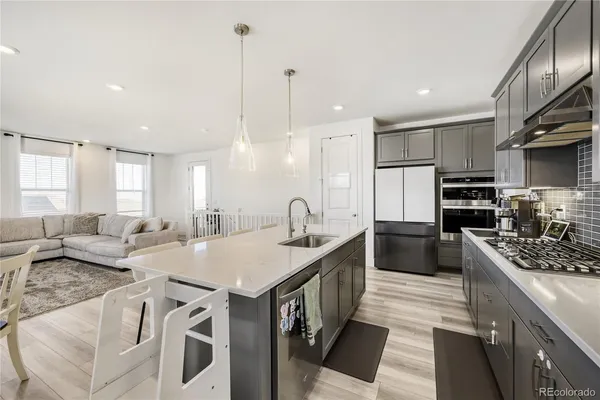 a kitchen with stainless steel appliances granite countertop a stove top oven a sink dishwasher a refrigerator and white cabinets with wooden floor