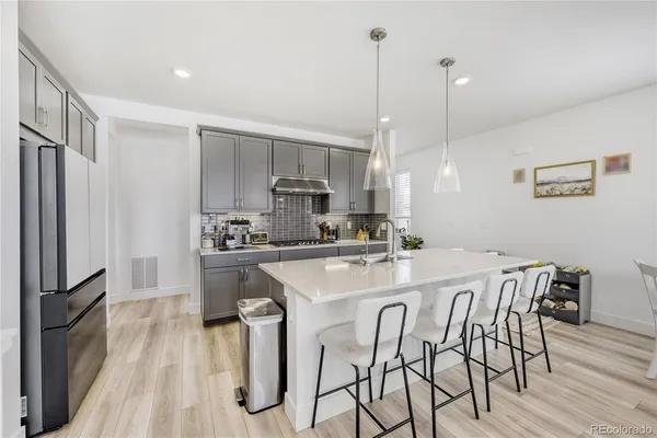 a kitchen with stainless steel appliances a table chairs refrigerator and wooden floor