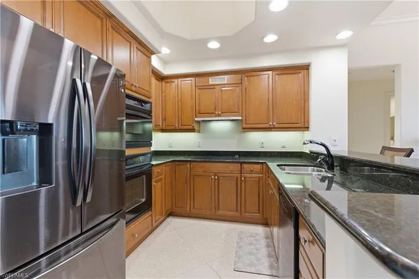 a kitchen with stainless steel appliances granite countertop a refrigerator and a stove top oven