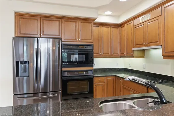 a kitchen with stainless steel appliances granite countertop a refrigerator a stove a sink a table and chairs