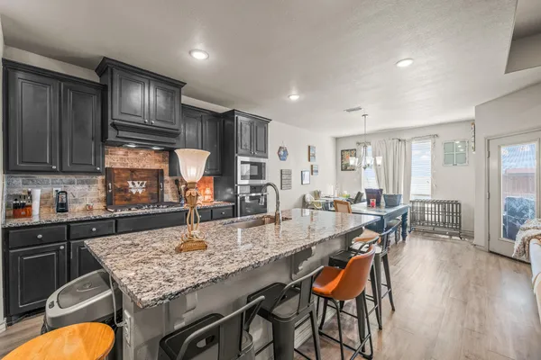 a view of a dining room and livingroom with furniture wooden floor a rug a painting and a chandelier