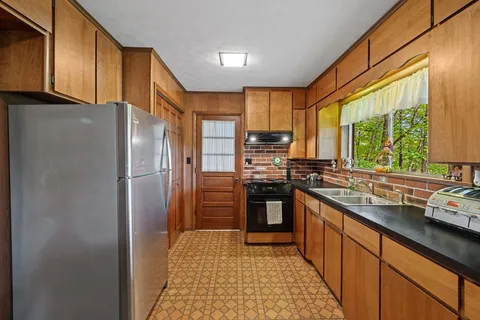a kitchen with stainless steel appliances granite countertop a refrigerator a sink a stove a washer dryer and a cabinets