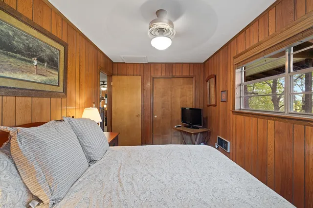 a bedroom with a bed tv and a window