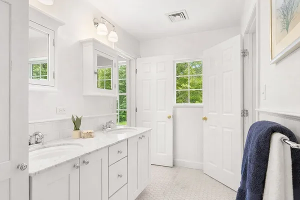 a bathroom with a double vanity sink a mirror and a bathtub