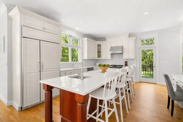 a kitchen with stainless steel appliances granite countertop a stove a refrigerator a sink a dining table and chairs with wooden floor