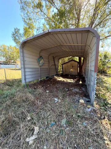 a view of a small house with a small yard and large tree