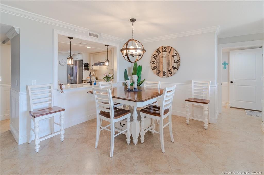 1701 Northeast Ocean Boulevard, Unit 103 Stuart, FL 34996 - Photo 15 of 46 a view of a dining room with furniture wooden floor and a chandelier