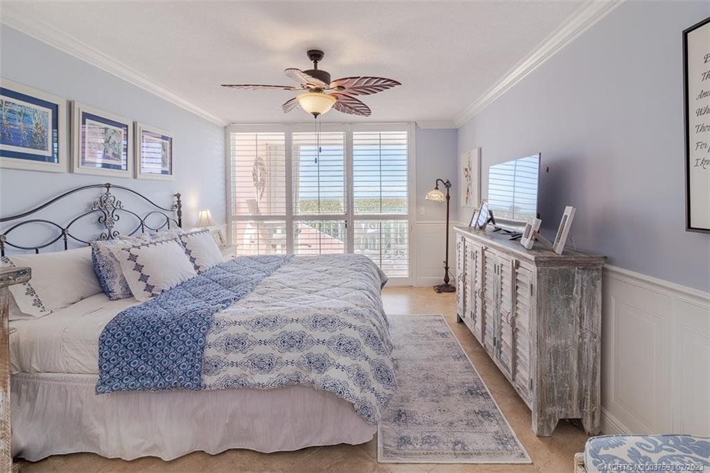 1701 Northeast Ocean Boulevard, Unit 103 Stuart, FL 34996 - Photo 19 of 46 a spacious bedroom with a bed a flat screen tv and windows
