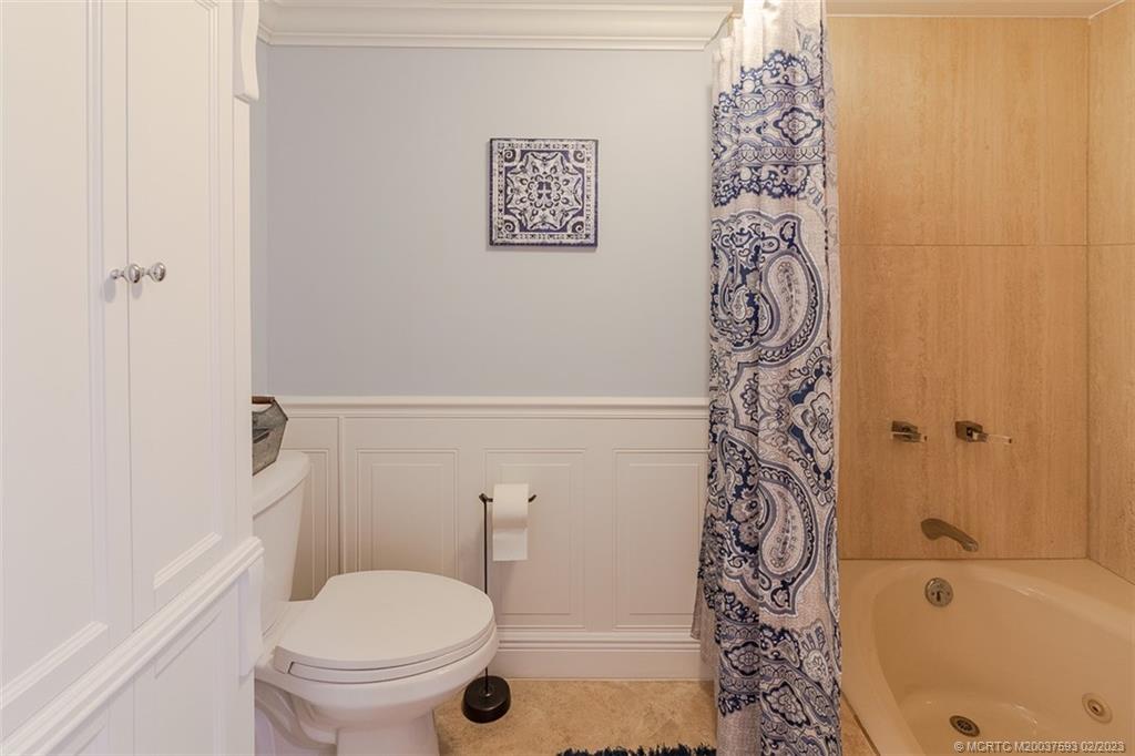 1701 Northeast Ocean Boulevard, Unit 103 Stuart, FL 34996 - Photo 22 of 46 a bathroom with a toilet and a shower curtain