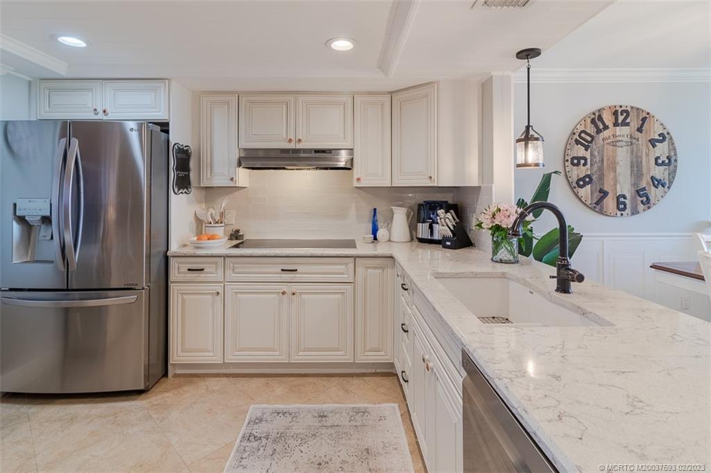 1701 Northeast Ocean Boulevard, Unit 103 Stuart, FL 34996 - Photo 10 of 46 a kitchen with stainless steel appliances granite countertop a sink a stove a refrigerator and a refrigerator with wooden floor