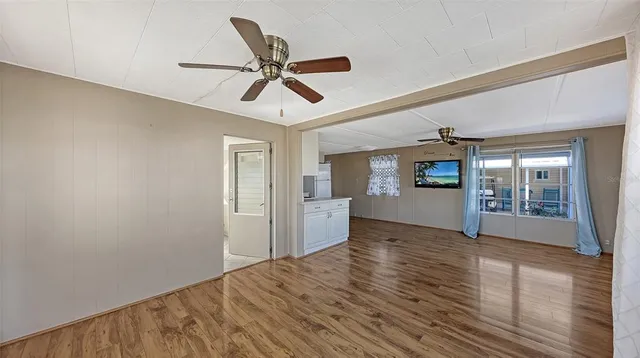 a view of an empty room with window and wooden floor