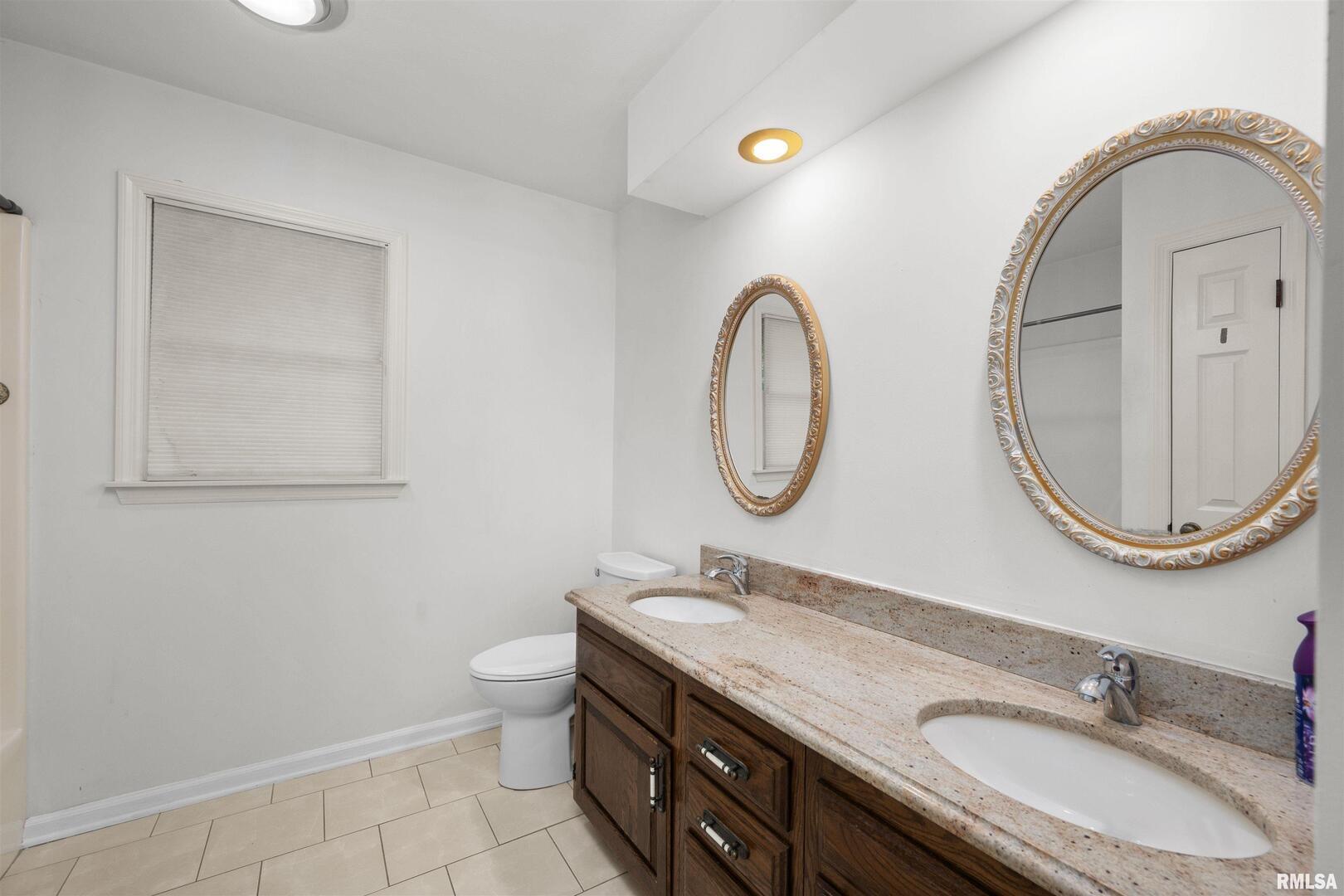 5 White Oak Court Moline, IL 61265 - Photo 43 of 57 a bathroom with a granite countertop toilet a sink and a mirror