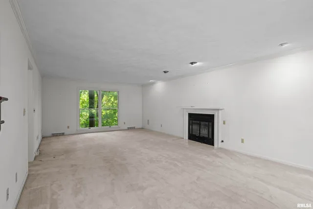 an empty room with windows and fireplace
