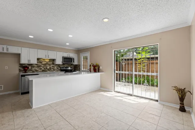 a view of kitchen with stainless steel appliances granite countertop a refrigerator and a stove top oven