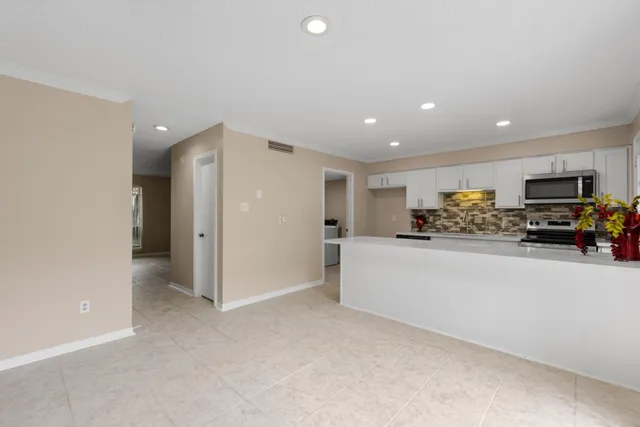 a kitchen with kitchen island granite countertop a sink and dishwasher a oven with white cabinets