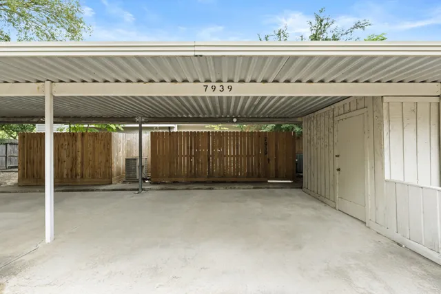 a backyard of a house with potted plants and large tree