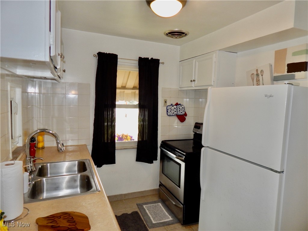 5961 Broadview Road Parma, OH 44134 - Photo 7 of 34 Kitchen featuring freestanding refrigerator, white cabinets, stainless steel electric range, light tile patterned floors, and light countertops