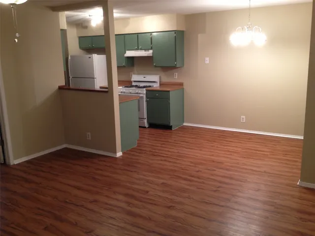 a view of a kitchen with a fridge and wooden floor