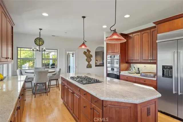 a kitchen with stainless steel appliances granite countertop a sink a stove and a wooden floors