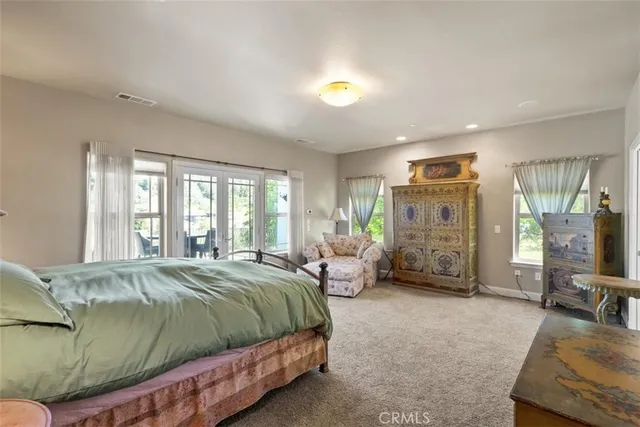 a spacious bedroom with a bed a chandelier and large windows