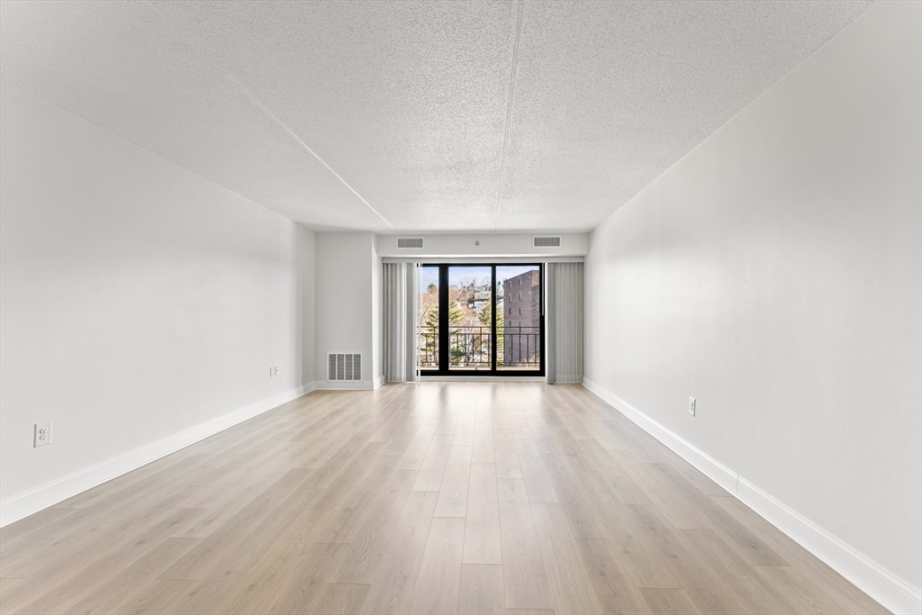 275 Main Street, Unit 404 Watertown, MA 02472 - Photo 11 of 39 an empty room with wooden floor and windows
