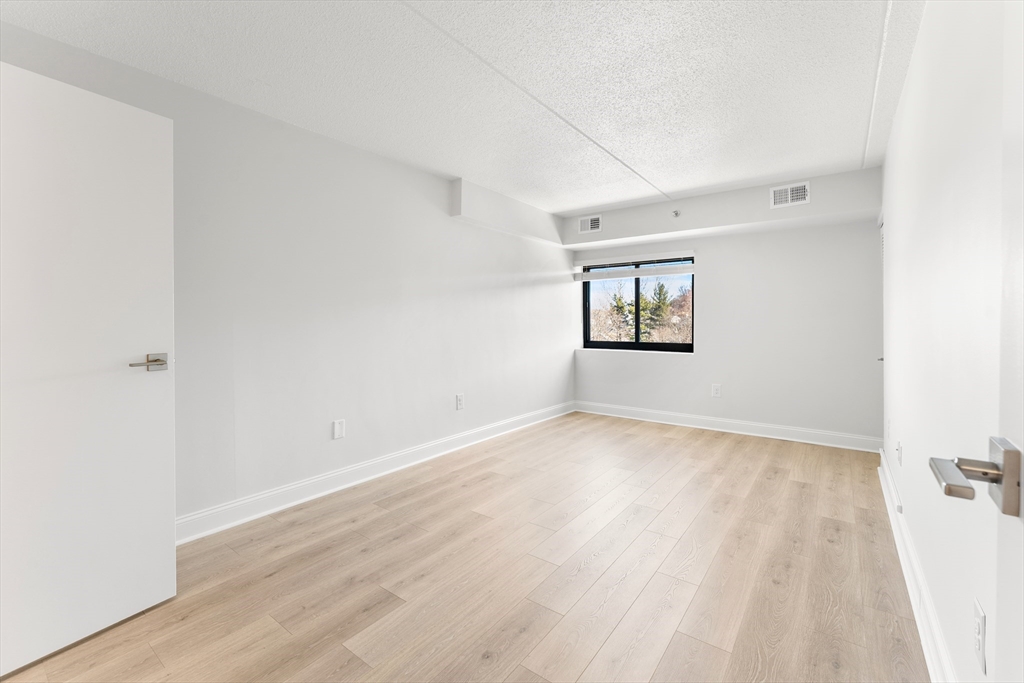 275 Main Street, Unit 404 Watertown, MA 02472 - Photo 27 of 39 an empty room with wooden floor and windows