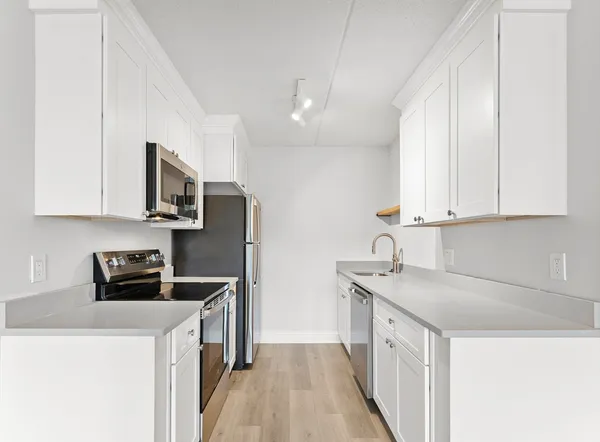 a kitchen with stainless steel appliances kitchen island granite countertop a sink a stove and white cabinets