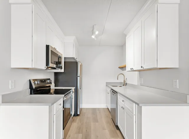a kitchen with stainless steel appliances kitchen island granite countertop a sink a stove and white cabinets