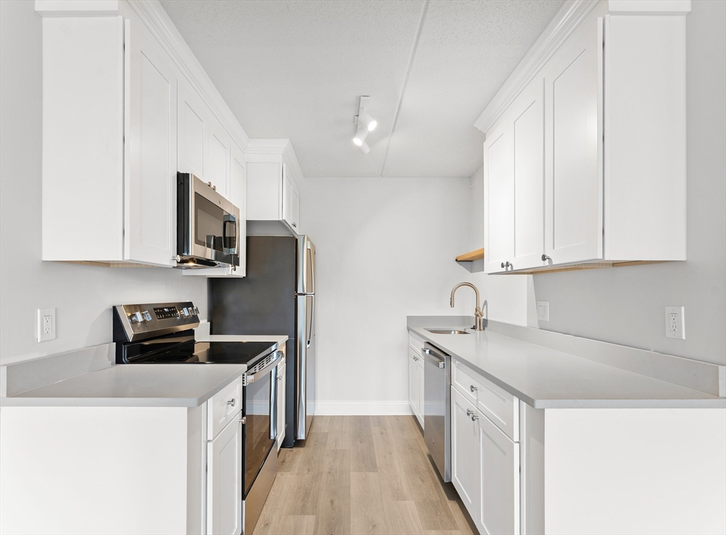 275 Main Street, Unit 404 Watertown, MA 02472 - Photo 3 of 39 a kitchen with stainless steel appliances granite countertop a sink stove and refrigerator