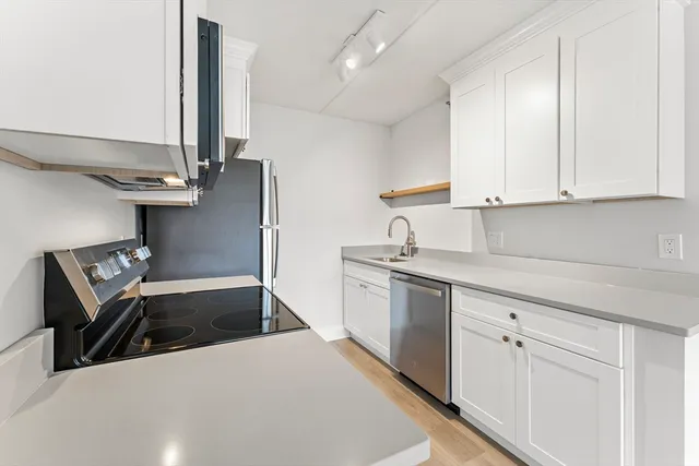 a kitchen with white cabinets and sink