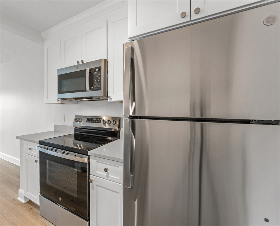 275 Main Street, Unit 404 Watertown, MA 02472 - Photo 10 of 39 a kitchen with stainless steel appliances white cabinets and a stove