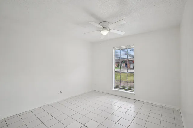 an empty room with windows and fan