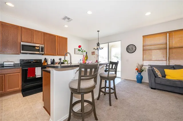 a kitchen with stainless steel appliances granite countertop a stove top oven a sink a dining table and chairs with wooden floor