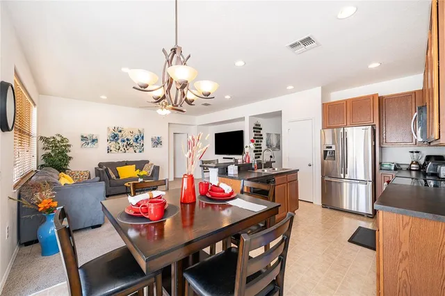 a kitchen with stainless steel appliances granite countertop a dining table chairs refrigerator and microwave