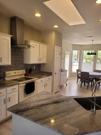 a kitchen with granite countertop a stove a sink and a refrigerator
