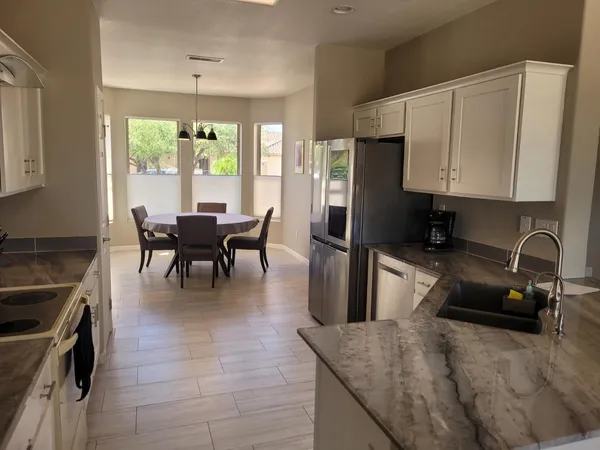 a kitchen with granite countertop a sink a counter top space appliances and cabinets