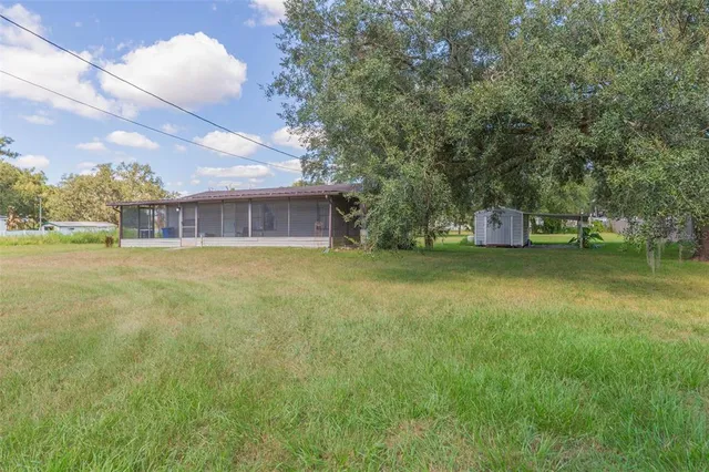 a view of a house with a yard and a large tree