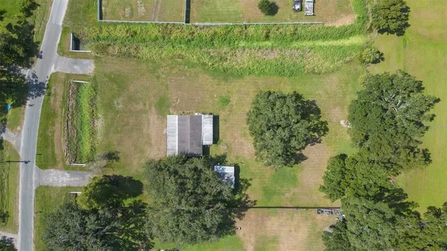 an aerial view of residential houses with outdoor space and trees