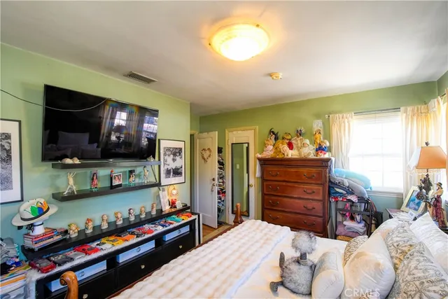 a bedroom with a bed and flat tv screen on the dresser