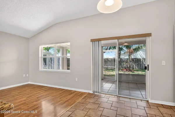 a view of an empty room with window and wooden floor