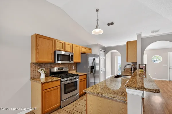 a kitchen with granite countertop a sink a stove top oven and cabinetry