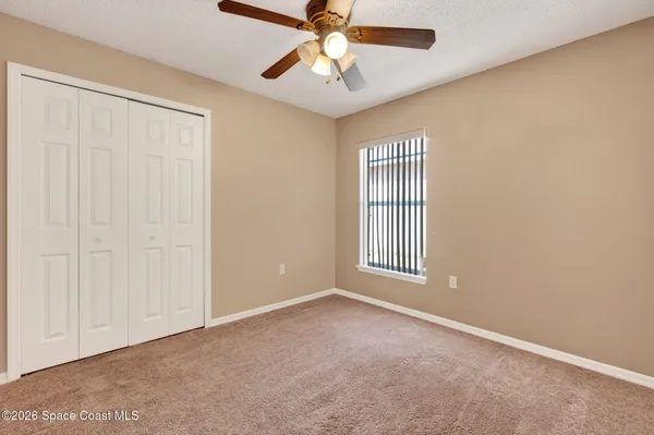 an empty room with windows and fan