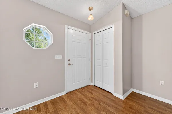 an empty room with wooden floor and windows