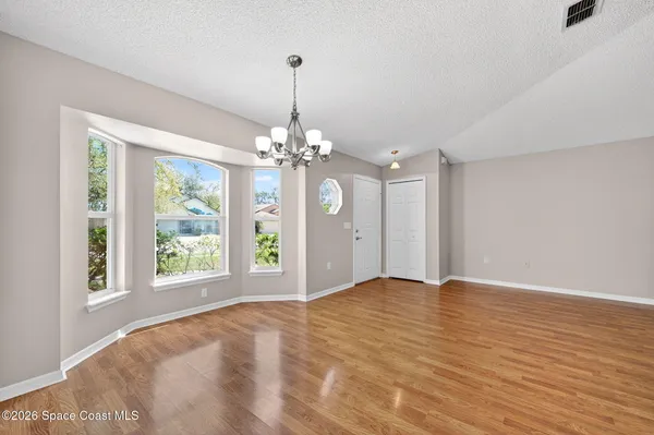 a view of an empty room with window and chandelier fan