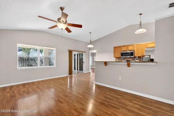 a view of a kitchen with wooden floor a ceiling fan and windows