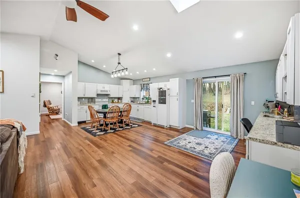 a living room with furniture kitchen view and a wooden floor