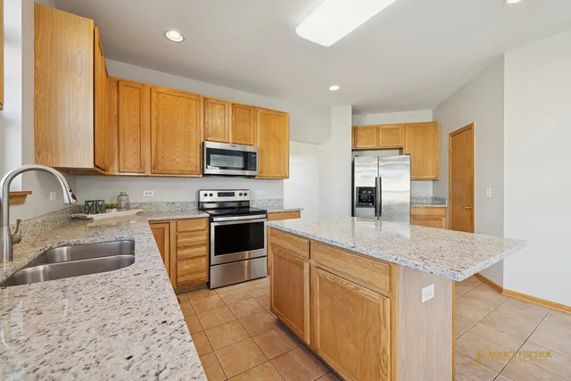 a kitchen with stainless steel appliances granite countertop a sink a stove and a refrigerator
