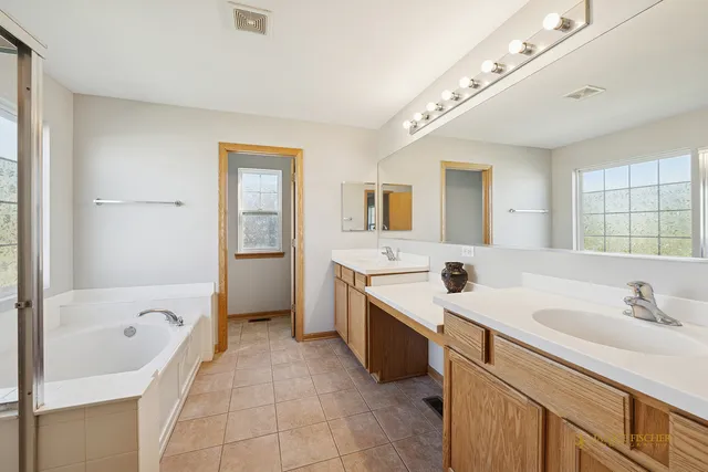 a spacious bathroom with a bathtub sink and mirror