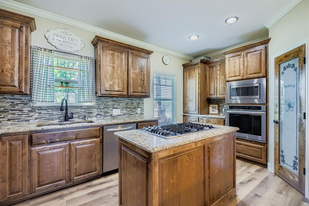 785 Schneider Road Howe, TX 75459 - Photo 22 of 40 Kitchen with crown molding, stainless steel appliances, healthy amount of natural light, a kitchen island, and light stone countertops
