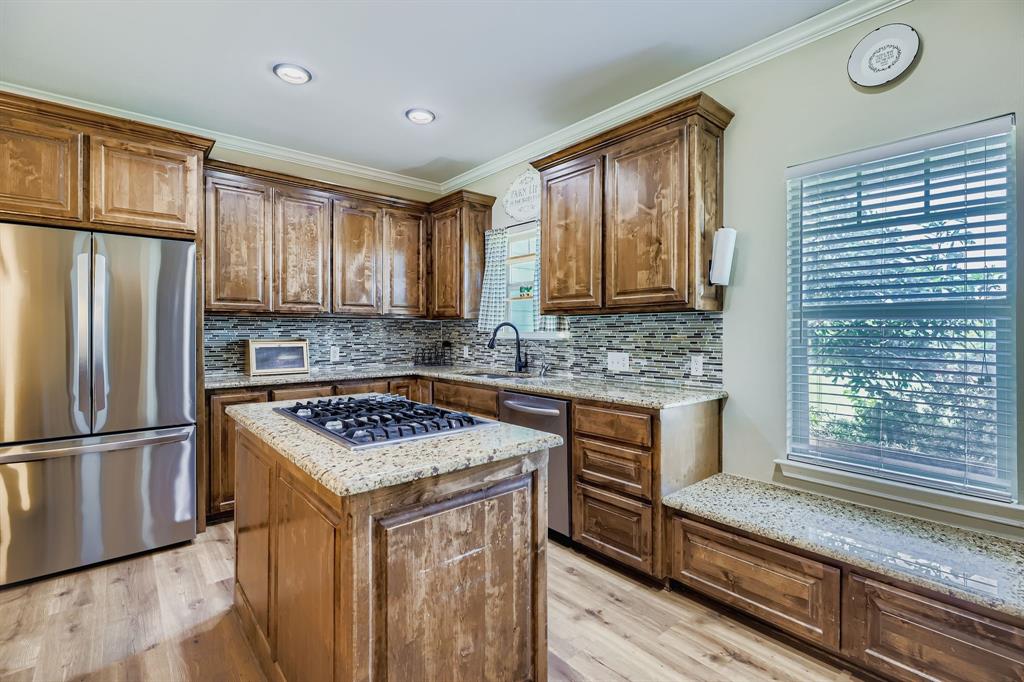 785 Schneider Road Howe, TX 75459 - Photo 23 of 40 Kitchen with stainless steel appliances, ornamental molding, light stone counters, light wood finished floors, and a kitchen island